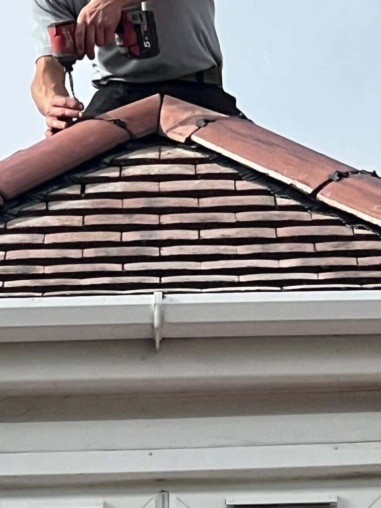 This is a photo of one of the operatives of MCM Roofing Repairs Andover installing new ridge tiles